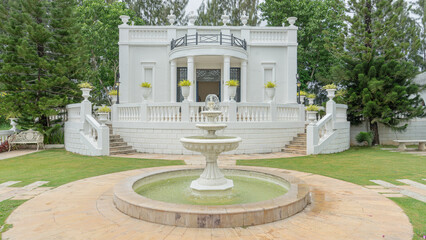 Location photos A three-tiered, circular white fountain with a stone tile floor. In the middle of...
