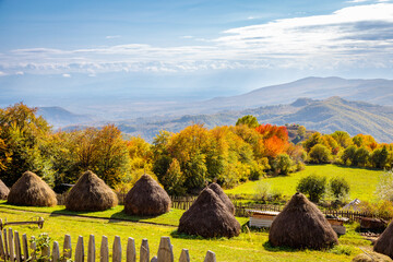 Autumn landscape with haystacks and mountains in the distance