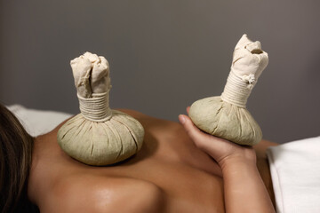 Healthy Thai method herb massaging, herbal compresses bag standing on lady back and hand at massage...