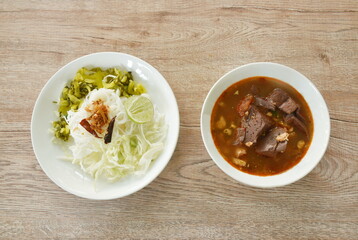 rice noodles fresh pickled  and fresh cabbage eat with spicy chop pork and  blood couple red cotton tree in curry sauce on plate