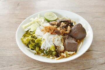 rice noodles fresh pickled  and fresh cabbage eat with spicy chop pork and  blood couple red cotton tree in curry sauce on plate