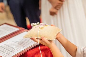 Closeup shot of the hands of a child holding wedding rings to give to the priest