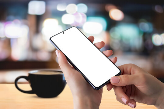 Smartphone mockup in hands with coffee mug on table, creating a cozy coffee time reading news concept. Perfect for showcasing digital content in a relaxed setting