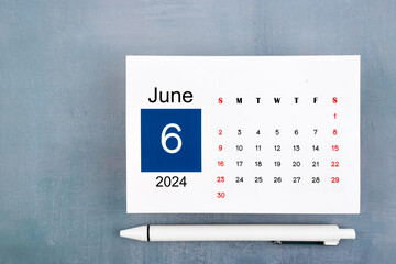 June Calendar 2024 page with pen on blue wooden