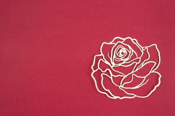 Carve of paper rose flower on a red cardboard background.