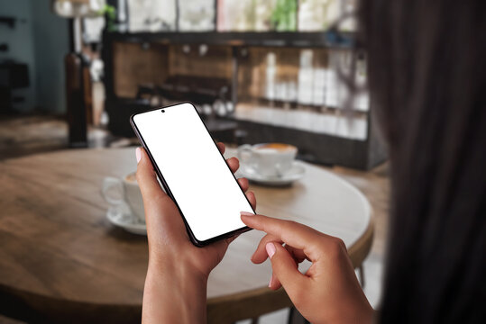Woman working on phone mockup in a cozy coffee shop, embodying the concept of relaxing free time. Using the phone for communication, blending work and leisure effortlessly