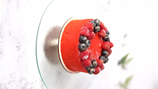 Red cake with raspberries and blueberries on a light background.