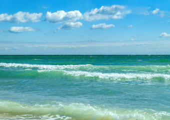 Sea waves and blue sky with white clouds.