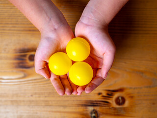 Kids holding yellow mini plastic balls on her hand.Top shot of holding balls slightly dirty kid hands