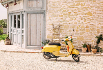 Nostalgic yellow scooter and plants by vintage building