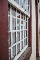 Uma janela rústica em uma cidade do interior do Brasil da época colonial com detalhes em madeira quadriculadas e vidros.