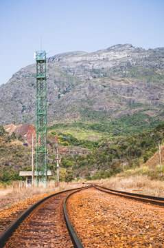 As montanhas no interior de Minas Gerais com o detalhe principal da linha ferra com os dormentes e britas e uma torre de comunica&ccedil;&atilde;o com uma edifica&ccedil;&atilde;o