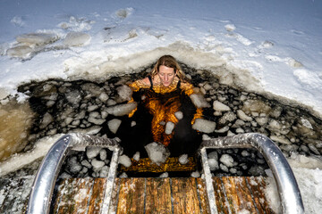 Stockholm, Sweden A woman ice bathing from a dock into a frozen lake.
