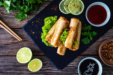 Spring rolls and sauces on wooden table
