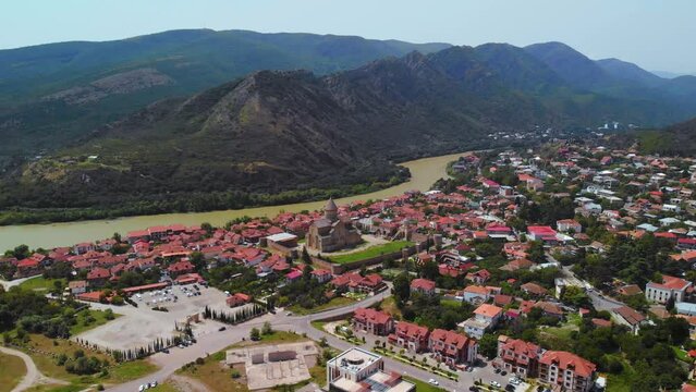 Beautiful aerial view of streets of Mtskheta village in Georgia. Mtkvari river. Summer sunny day. Travel and vacation. Svetitskhoveli Cathedral fortress in the center.