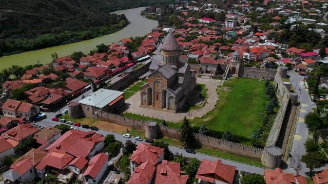 Beautiful aerial view of streets of Mtskheta village in Georgia. Mtkvari river. Summer sunny day. Travel and vacation. Svetitskhoveli Cathedral fortress in the center.