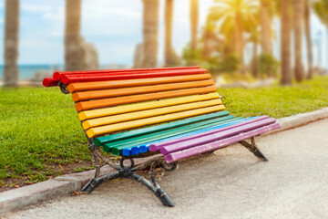 Colorful empty lgbt rainbow painted bench in a park