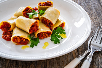 Paccheri con ragù alla bolognese - noodles with bolognese  sauce on wooden table