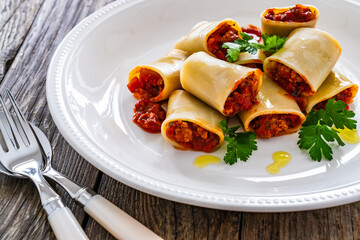 Paccheri con ragù alla bolognese - noodles with bolognese  sauce on wooden table