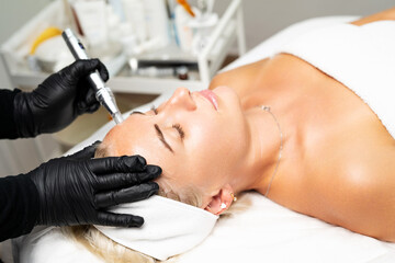 Microneedle RF lifting procedure. A cosmetologist performs a facial rejuvenation procedure on a...