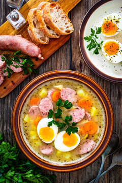  Sour rye soup with sausages and boiled eggs on wooden table