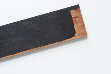 grungy wooden slat painted or stained black with unpainted joint areas and old fastener holes on white