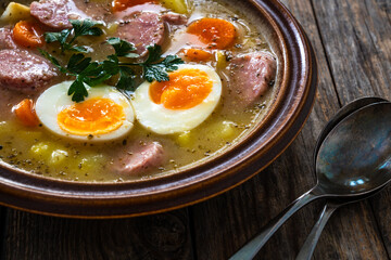  Sour rye soup with sausages and boiled eggs on wooden table