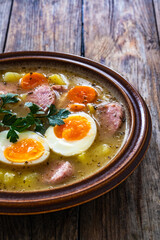  Sour rye soup with sausages and boiled eggs on wooden table