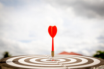 Close up shot red darts arrows in the target  of dartboard center on dark blue sky background. Business target or goal success and winner concept.