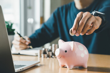 Obraz na płótnie Canvas Hand putting coins in a piggy bank for save money and Saving Money concept.