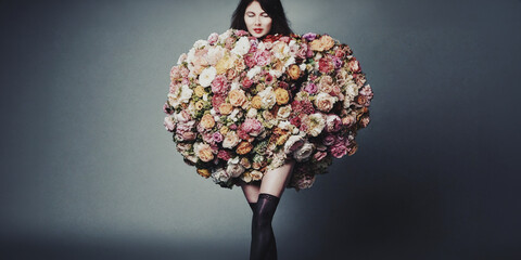 primo piano ritratto artistico di donna avvolta in un grande bouquet di fiori colorati, sfondo con luce diffusa
