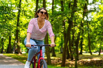 Obraz premium Beautiful mid adult woman riding bicycle in city park 
