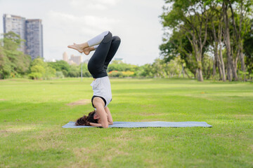 Young women have a beautiful bodies, Playing yoga in an elegant posture, in the green park, is a concept of people's recreation and health care concept. blurred background