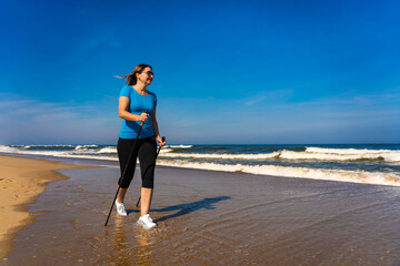 Nordic walking - beautiful woman exercising on beach