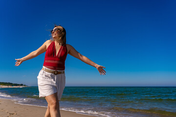 Fototapeta na wymiar Beautiful mid adult woman walking on sunny beach 