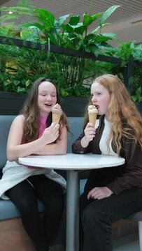Teenagers, two girls, friends, eating ice cream in a park in the Mall, red hair, fair-skinned, summer communication, meeting, ice cream cone, chocolate and vanilla.