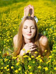 Naklejka na ściany i meble Young beautiful blond girl laying on the daisy flowers field