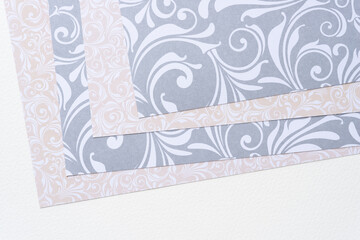 layered decorative scrapbooking sheets with floral patterns or swirls in silver gray and beige