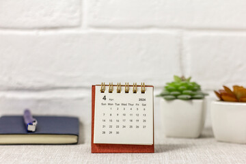 Desk calendar for April 2024 and a clock on the table. - obrazy, fototapety, plakaty