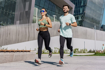 Fit couple jogging in sync in an urban setting, enjoying a healthy lifestyle together.