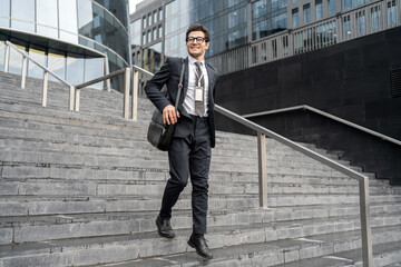 Confident businessman strides down city steps, smart in a suit with ID badge.