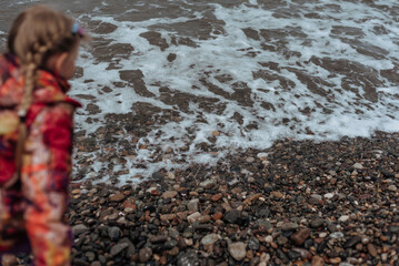 Coast. Cloudy day on the sea beach. Girl on the beach in a jacket