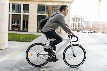 Businessman cycling to work in the city, dressed in smart casual attire with a sleek black backpack.