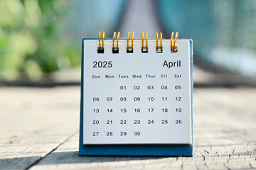 April 2025 white calendar with green blurred background. New year concept.