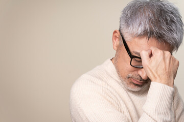 Obraz premium メガネをかけたグレーヘアのミドル世代日本人男性のポートレート/悩んでいる