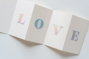 fan folded blank cards with sticker letters composing the word love and arranged on blank paper