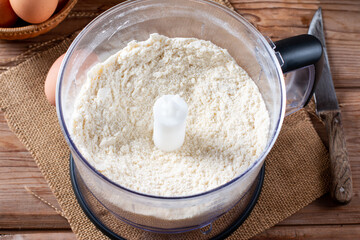 Flour in bowl with butter and handheld pastry blender.