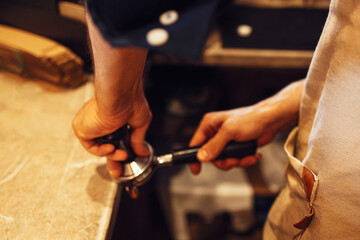 Barista grinding freshly roasted coffee beans from a professional modern electric grinder into a powder