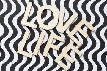 trendy sign with wood letters, or the words "love life" on paper with black and white wavy stripes