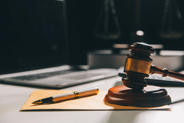 image of judge's hammer, scales lady of justice, law book, laptop computer and contract documents with pen concept of law and justice.
